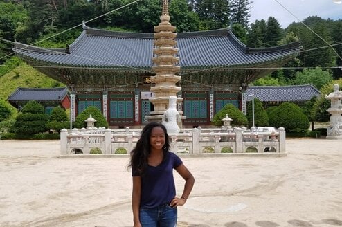 A young woman poses in front of a temple in South Korea.