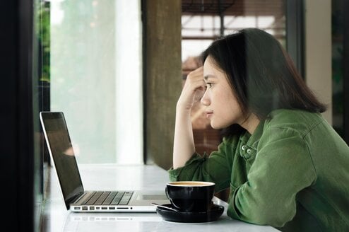Person using laptop and drinking coffee