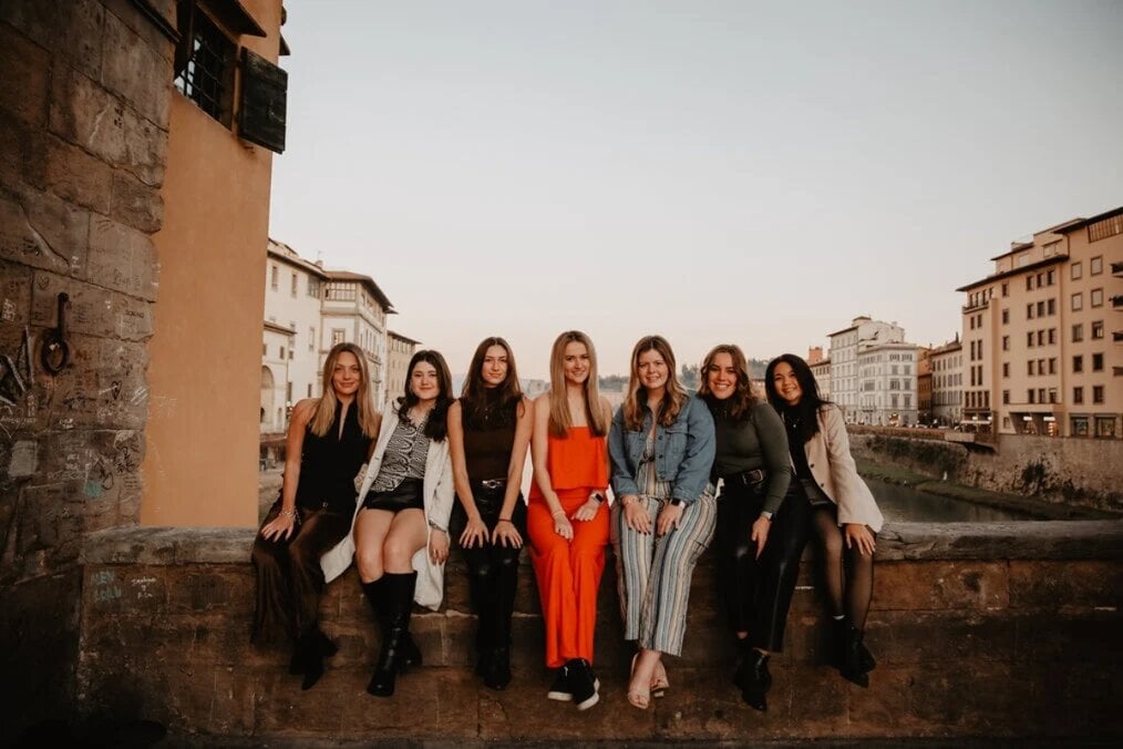A group of friends sat on a wall with a backdrop fo the city