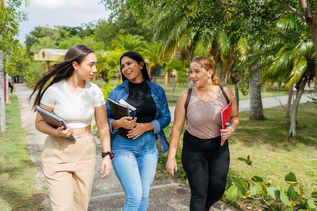 Three women college students walk together and laugh.