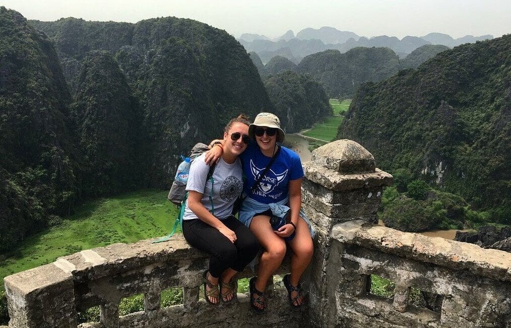 Two travelers sitting in front of mountains.