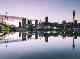 Twilight cityscape of Auckland, New Zealand reflected in water.