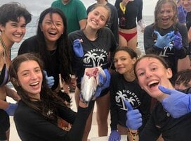 Group of teens on boat dissect fish