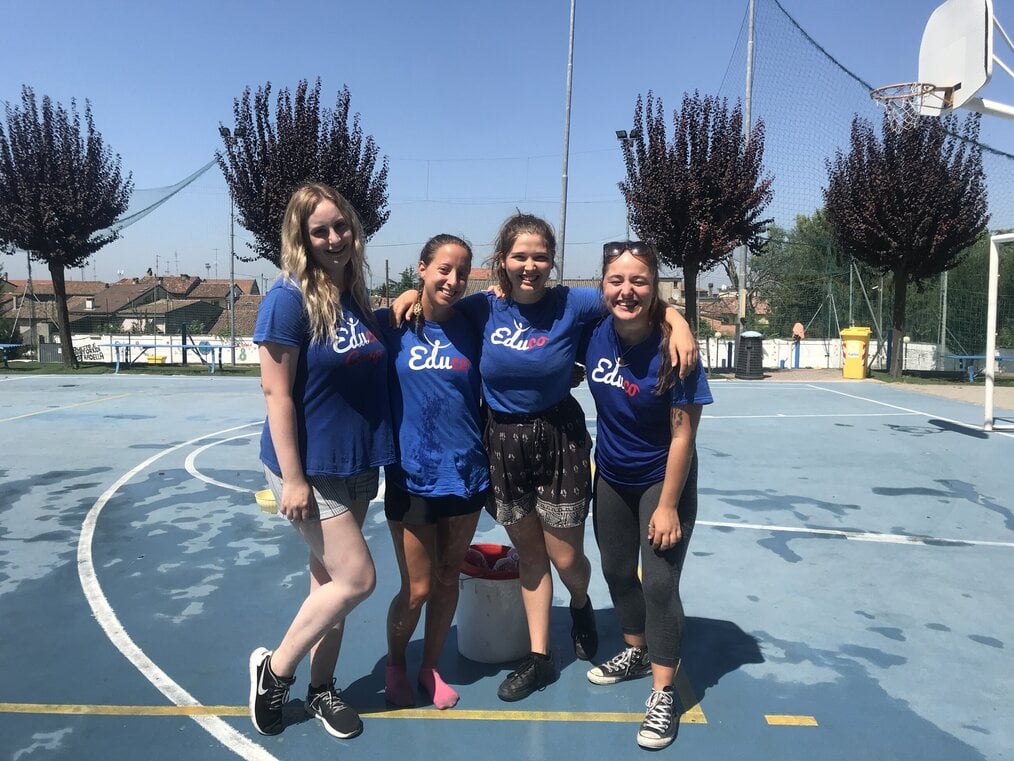 4 summer camp leaders smiling on a basketball court