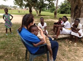A young Kenyan child child sleeps in the arms of a female Village Book Builders volunteer.