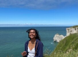 Student sitting on a hill overlooking a body of water, enjoying all that France has to offer