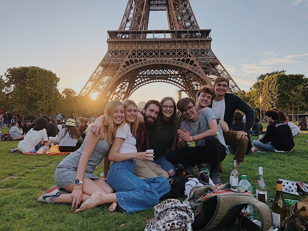 A group of students pose in front of the Eiffel Tower in Paris.