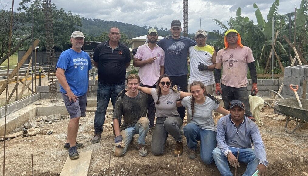 Volunteers stand at building site.