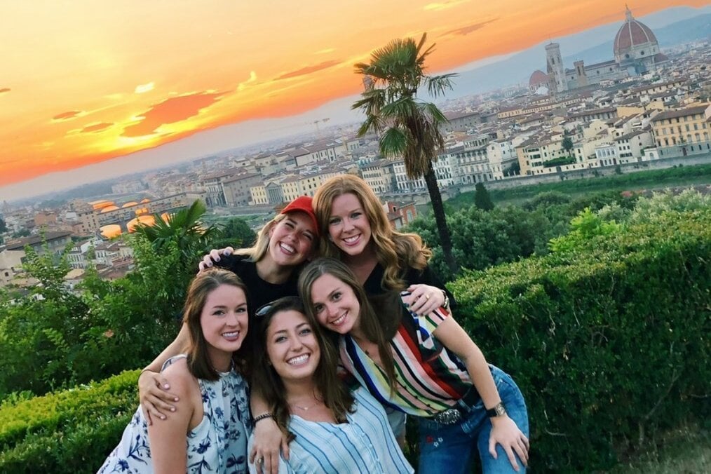 Five friends posing in front of a city view and sunset 