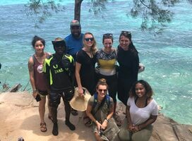 A group of students posing in front of a body of water.