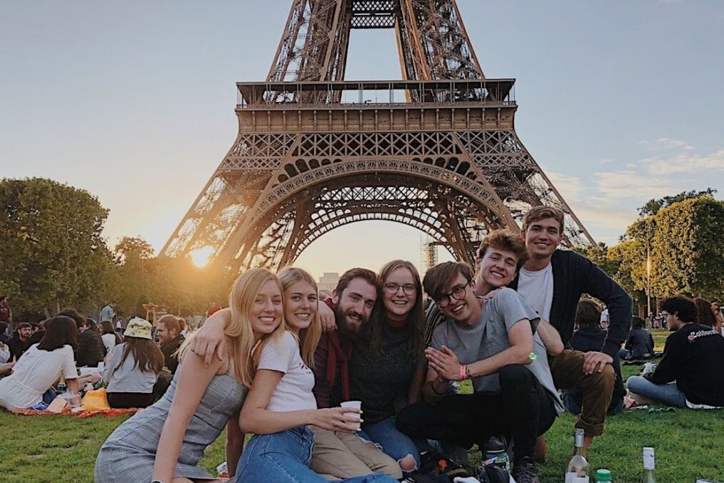 Study abroad students relaxing by the Eiffel Tower in Paris