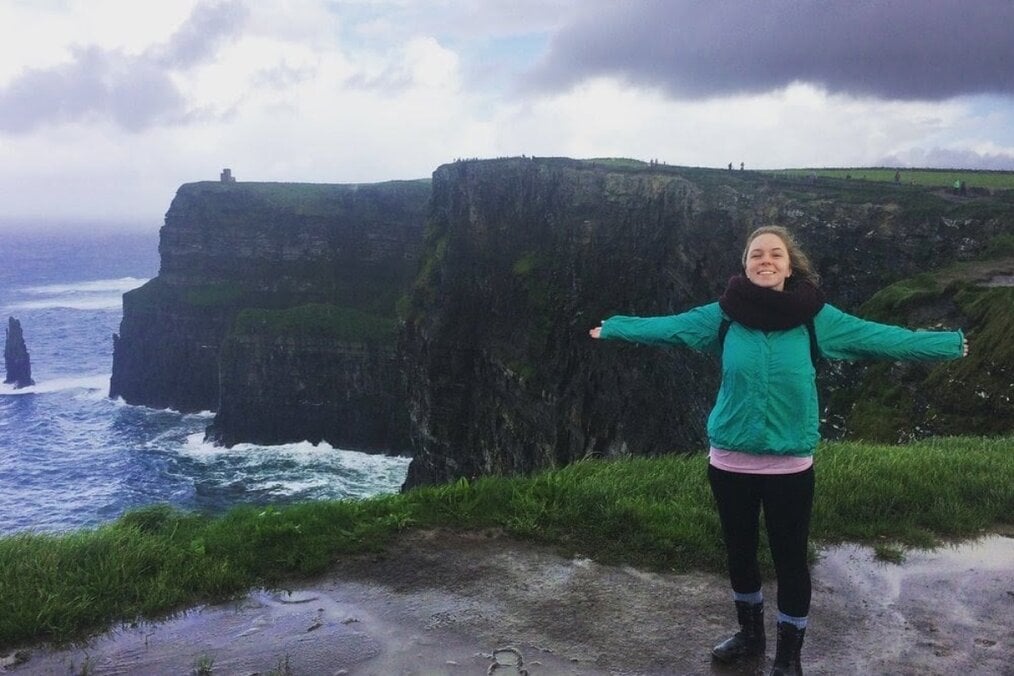 A person standing on a cliff near the sea