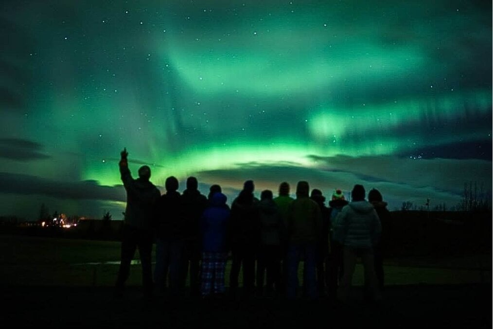 A group of people staring up at the northern lights at night 