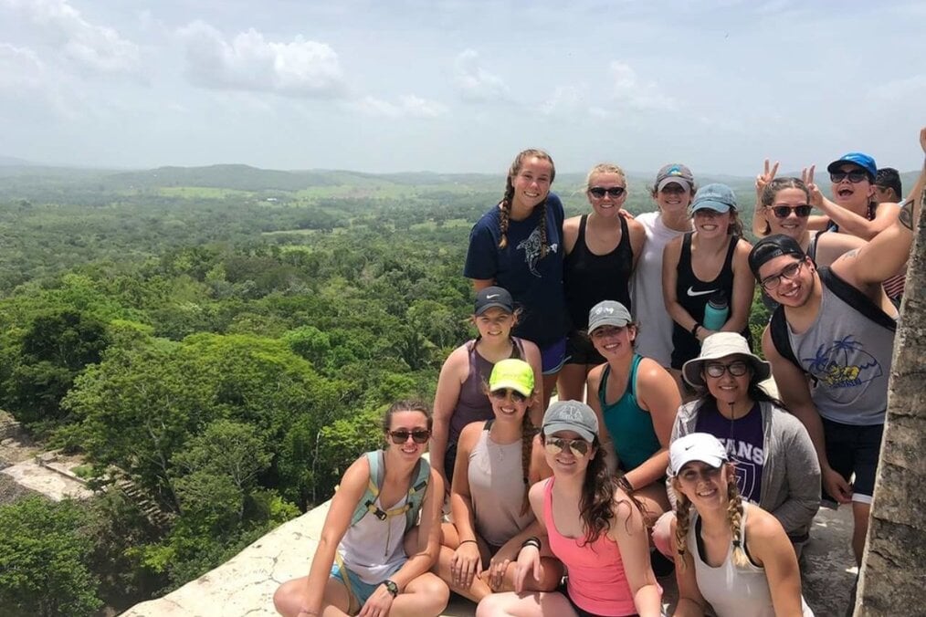 A group of friends on a mountain overlooking a green landscape