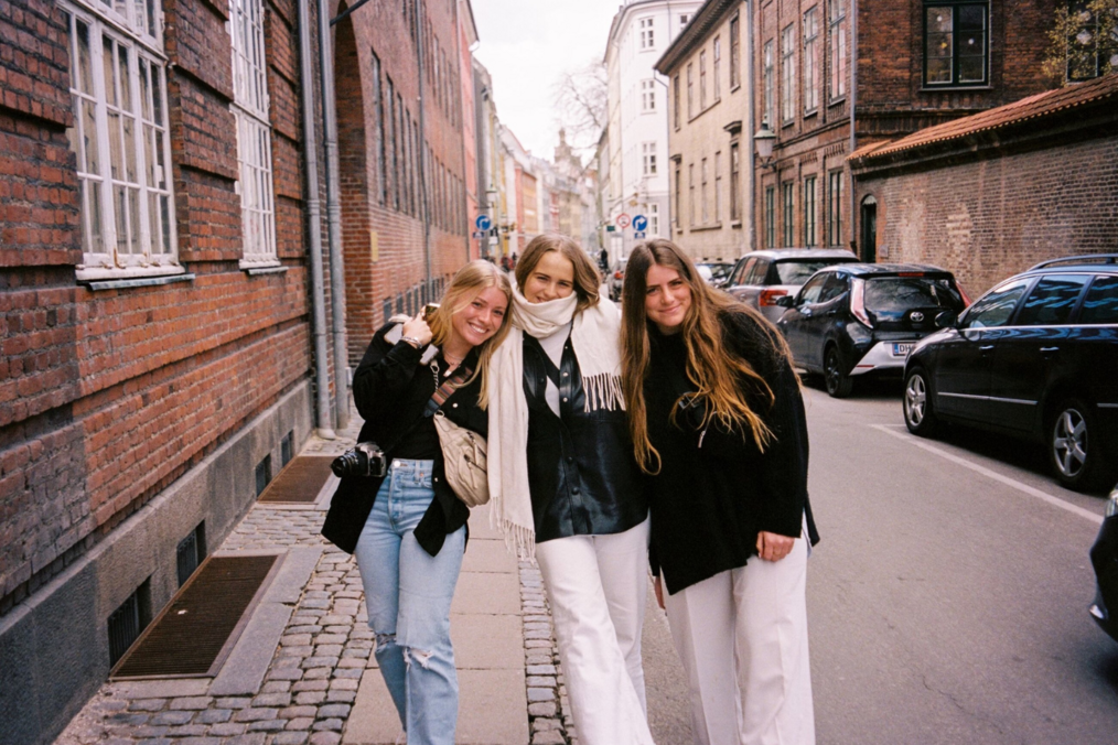 Three students smiling walking down a street