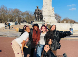 group of students pose in front of monument in london