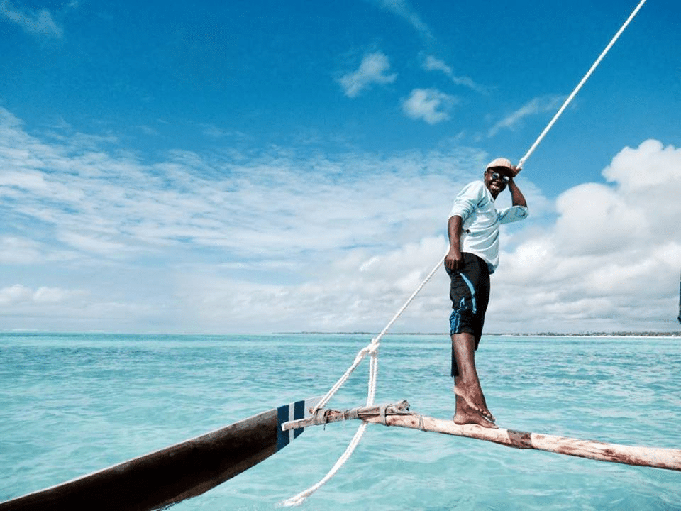 A man stands on the rigging of a ship.